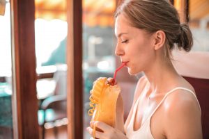 https://www.pexels.com/photo/woman-in-white-tank-top-drinking-orange-juice-3755827/